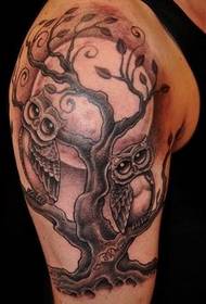 En uggla och kvist tatuering på armen
