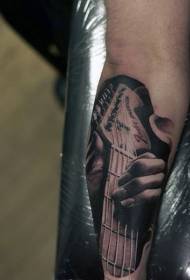 Рука рэалістычны чорна-белы ўзор татуіроўкі на гітары