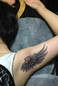 Ragazza in ginocchio con un disegno del tatuaggio ala