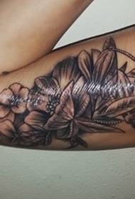 Exquisito tatuaje de flores negras y grises en el interior del brazo grande