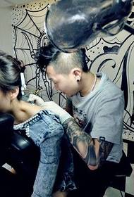 Gepersonaliseerde tattoo-artiest geeft een tatoeage aan een mooie vrouw