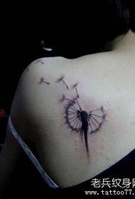 मुलीच्या खांद्यावर एक नाजूक पिवळ्या रंगाचा गोंदण