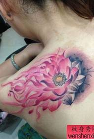 Flickans axel med ett färgglad tatueringsmönster för bläcklotus