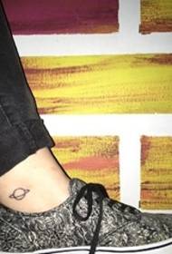 ຜູ້ຊາຍຂໍ້ຕີນກ່ຽວກັບເສັ້ນສັກສີ ທຳ ມະດາສີ ດຳ ດາວທຽມສັກລາຍສັກຮູບ Saturn Tattoo