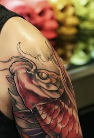 Ison miehen käsivarsi punaisella iso kalmari-tatuointikuviolla