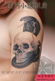Мужская рука, красивая кобра с татуировкой черепа