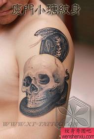 Brazo masculino guapo cobra con patrón de tatuaje de calavera