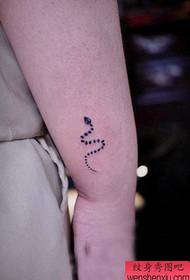 рука девушки с татуировкой тотема змея