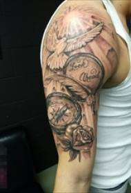 Knabo diras, ke brako de nigra malsata skizo kreema birdo kaj horloĝa roza bildo de tatuaje