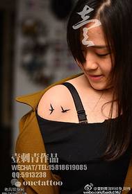Two bird tattoos on the shoulders