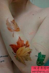 Дјевојчица на рукама прекрасан обојени узорак тетоваже јаворовог лишћа