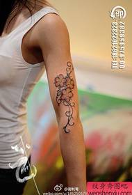 O braço da menina bela cor popular padrão de tatuagem de flor de cerejeira