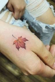 A mão da menina nas costas pintou imagem de tatuagem de folha de bordo material de planta gradiente