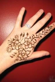 Lámh na mban ar chúl an phictiúir de phlandaí cruthaitheacha bláth álainn tattoo