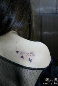 Bahu perempuan dengan huruf bahasa Inggris dan tato burung