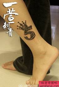 una corona e un disegno del tatuaggio digitale sulla gamba della ragazza