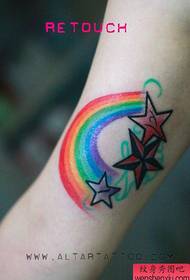 Bras de fille à l'intérieur d'un motif de tatouage étoile à cinq branches arc-en-ciel
