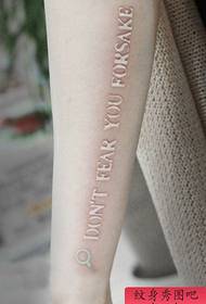 Красивая девушка рука с красивым белым рисунком татуировки буквы