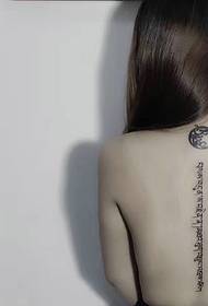 Mote jente ryggraden med et sanskrit tatoveringsmønster