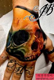 un popular tatuatge de crani de color a la part posterior de la mà