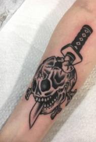 Boy's arm op swartgrys skets kreatiewe dolk en skedel tattoo foto