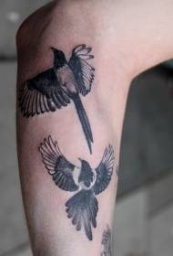 kaksi harakkaa lentämässä käsivarren tatuointikuviossa