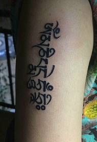 corak tatu tunggal Sanskrit di bahagian luar lengan