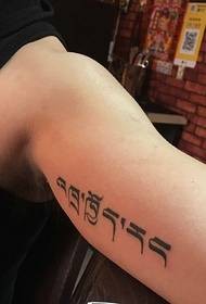 semplice figura femminile con piccolo tatuaggio sanscrito all'interno del braccio