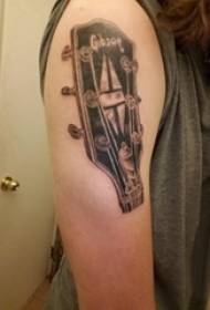Braccio del ragazzo sull'immagine creativa nera del tatuaggio del bordo della chitarra letteraria di schizzo grigio nero