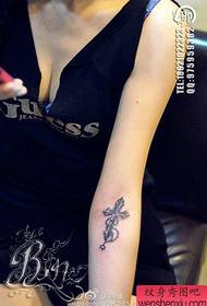 Krahu i vajzës me një model tatuazhi të vogël kryq