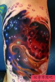 Tatuagem colorida de céu estrelado na parte interna do braço