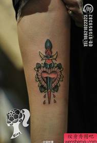 Braccio da bambina con un piccolo pugnale e motivo a tatuaggio d'amore