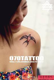 fată drăguță pe un umăr cu un model popular de tatuaj de înghițire