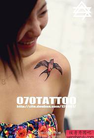 bella ragazza su una spalla con un popolare modello di tatuaggio rondine