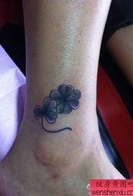 un piccolo tatuaggio in bianco e nero a quadrifoglio sulla caviglia della ragazza