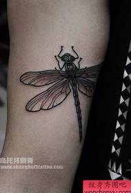 a small dragonfly tattoo pattern on the inside of the arm