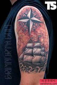 un bel tatuaggio con la bussola della barca a vela sul grande braccio
