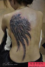 Dominējošā meitene ar superreālistisku spārnu tetovējuma attēlu