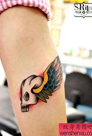 एक टैटू और पंख टैटू पैटर्न के साथ लड़की की बांह