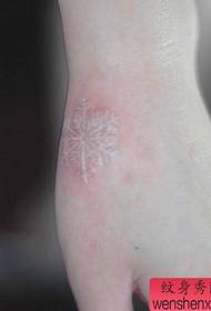 Main de fille un motif de tatouage petit flocon de neige blanc