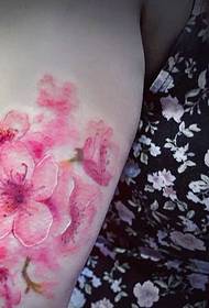 ყვავილის ქალის მკლავს აქვს ალუბლის ყვავილი ტატუირების სურათი ძალიან ლამაზია