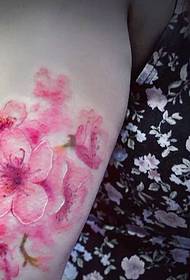 U bracciu di a donna di u fiore hà una stampa di tatuaggio di fiore di ciliegia hè assai bella