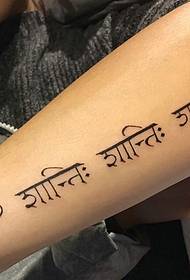 tatuaje sánscrito elegante na parte exterior do brazo
