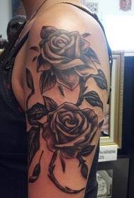 brazo feminino sobre tatuaje de rosa gris negra